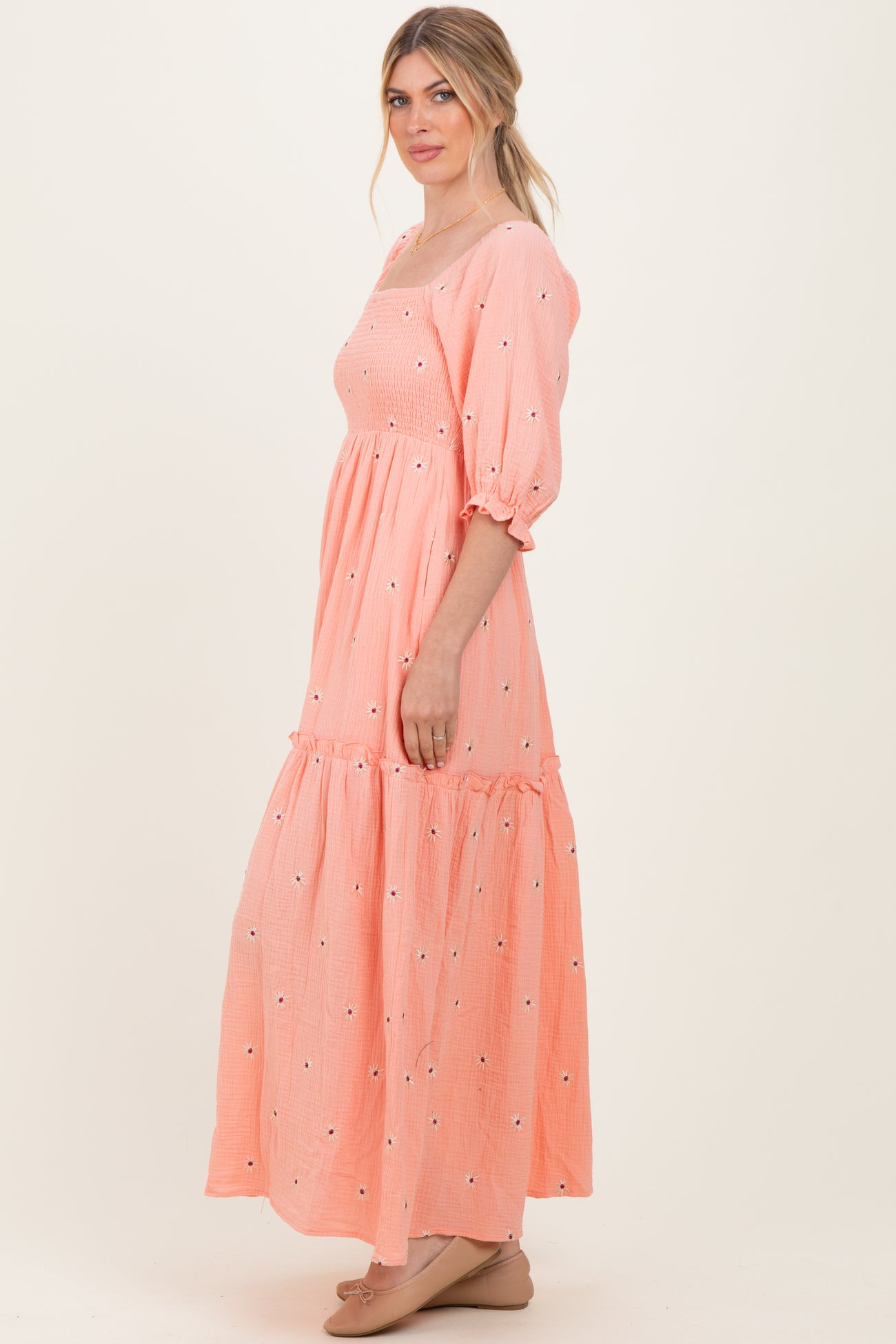 woman wearing a pink floral embroidered maxi dress with puff sleeves and a tiered skirt