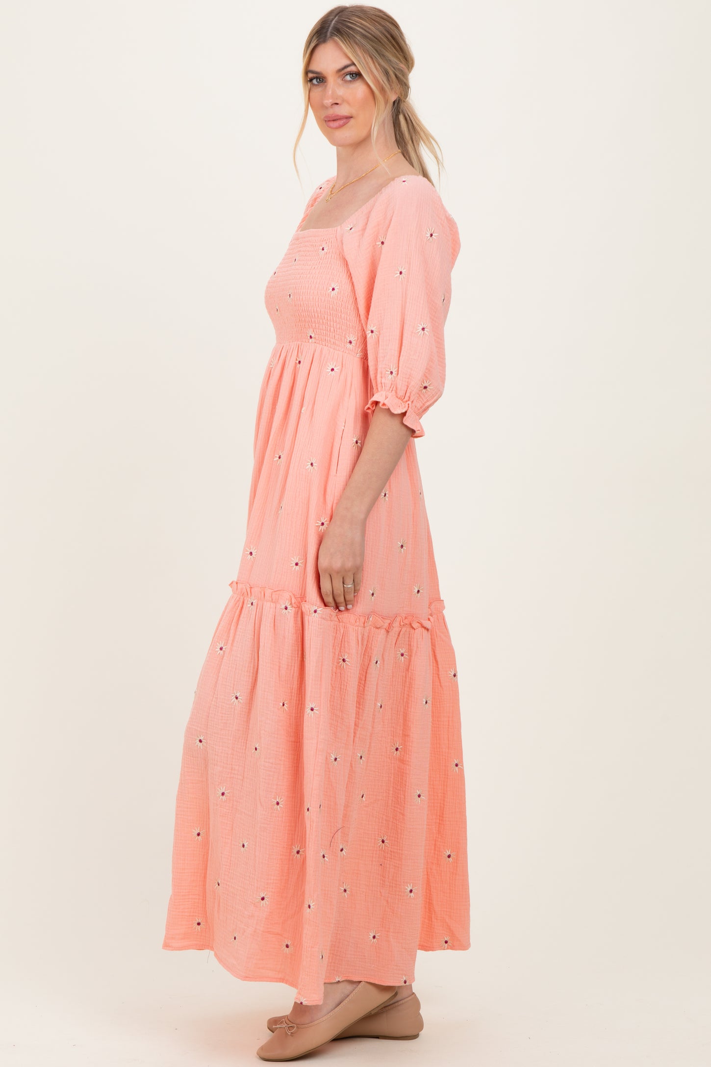 woman wearing a pink floral embroidered maxi dress with puff sleeves and a tiered skirt