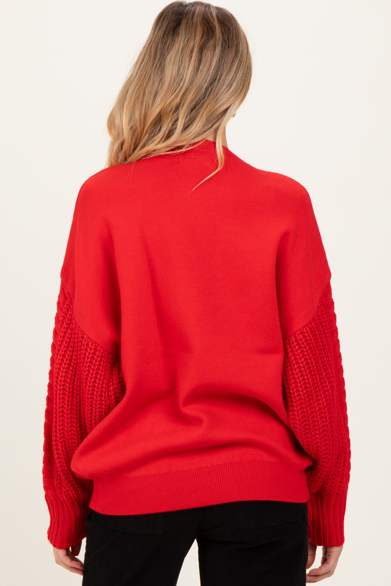 woman wearing a red maternity sweater with textured knit sleeves, showing the back view