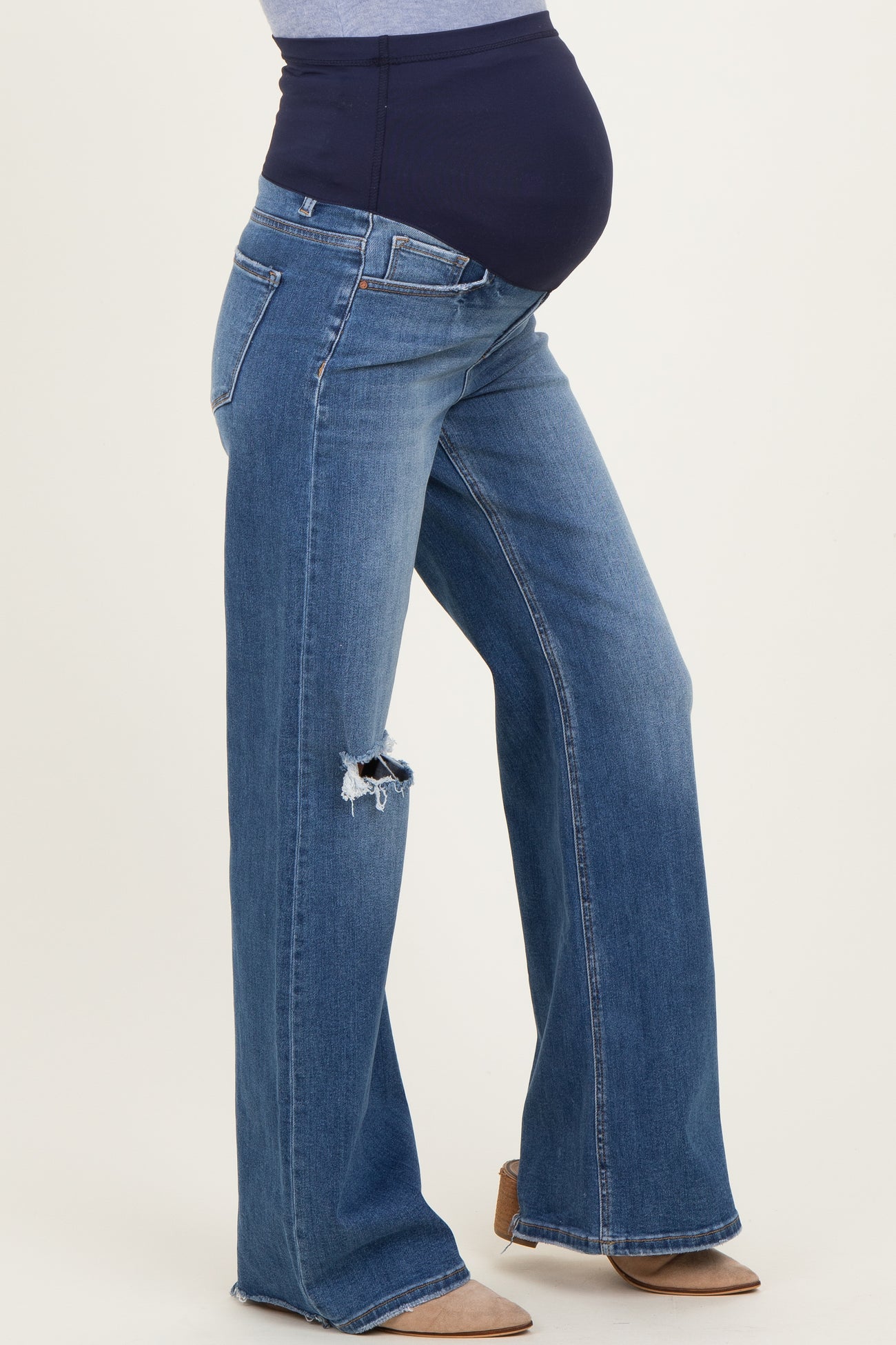 maternity wear blue distressed flare jeans with a black over-the-bump panel and visible baby bump