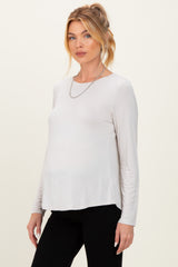 woman wearing a light beige long sleeve maternity top with a relaxed fit and a visible baby bump