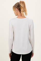 woman wearing a light gray long sleeve maternity top, viewed from the back with a slightly curved hem