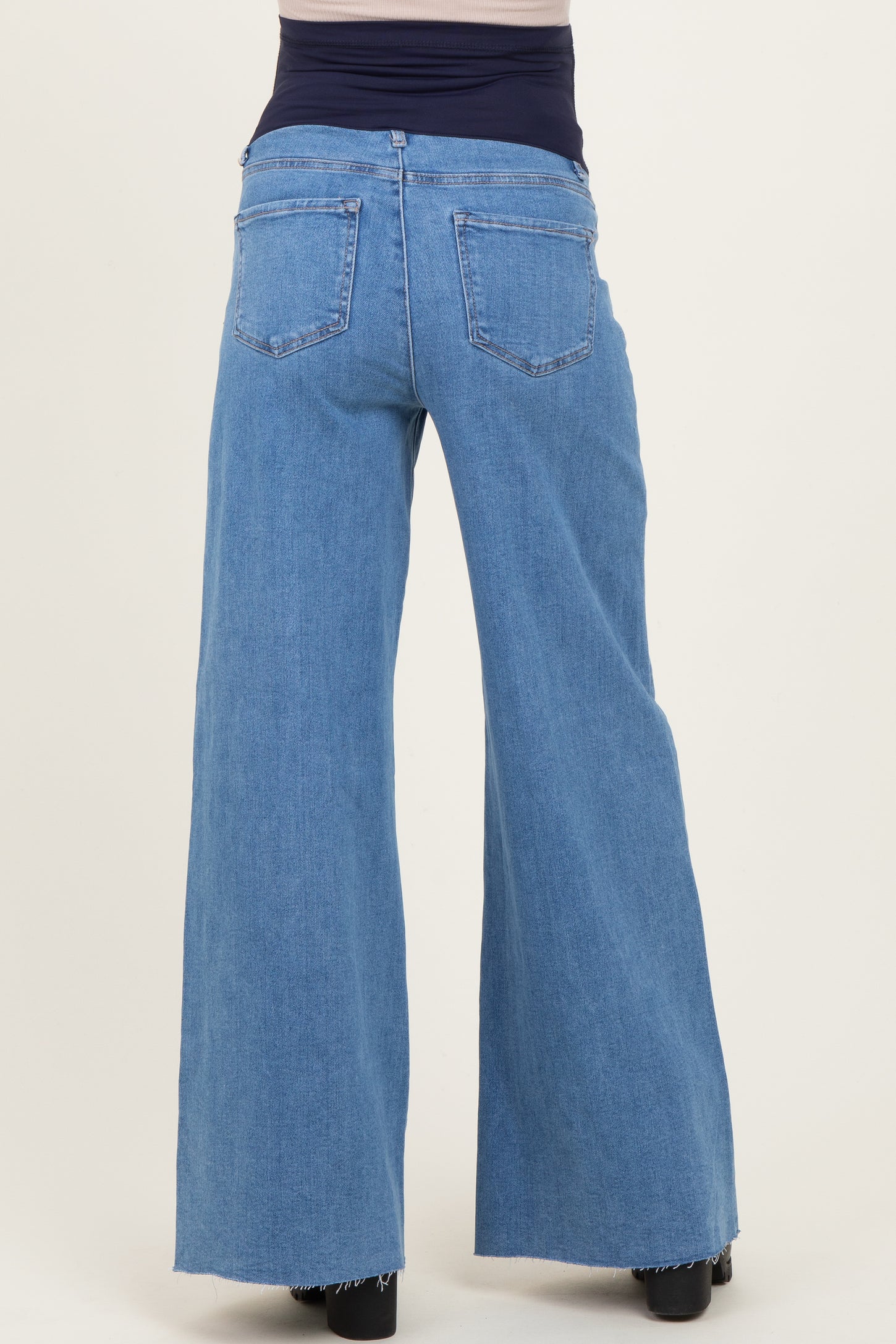 woman wearing light blue maternity wide-leg jeans with a frayed hem, showing the back view