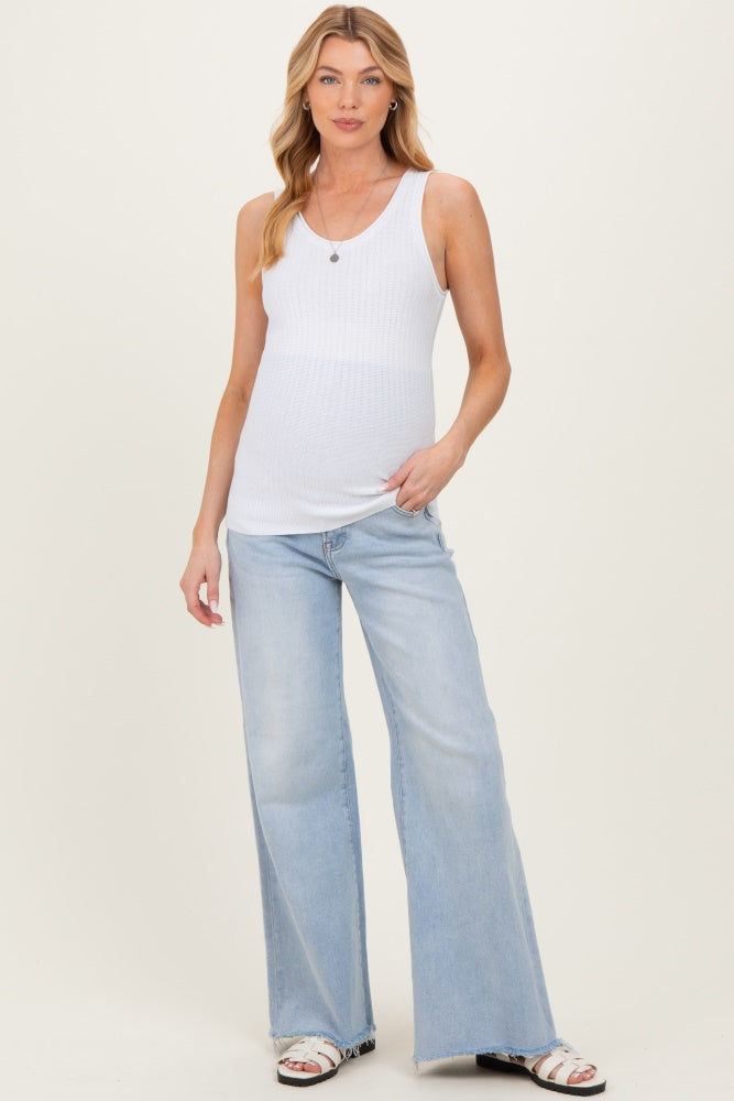 woman wearing a white ribbed maternity tank top and light blue wide-leg jeans with a visible baby bump