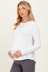 woman wearing a white long sleeve maternity top and holding her baby bump