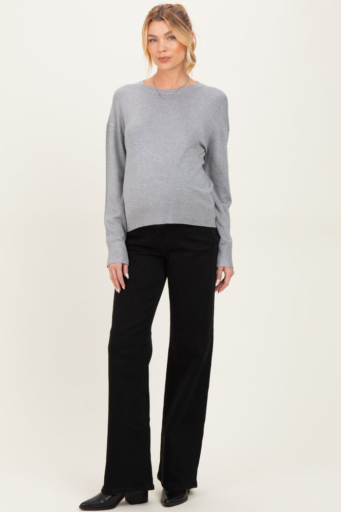 woman wearing a gray maternity sweater and black pants with a visible baby bump