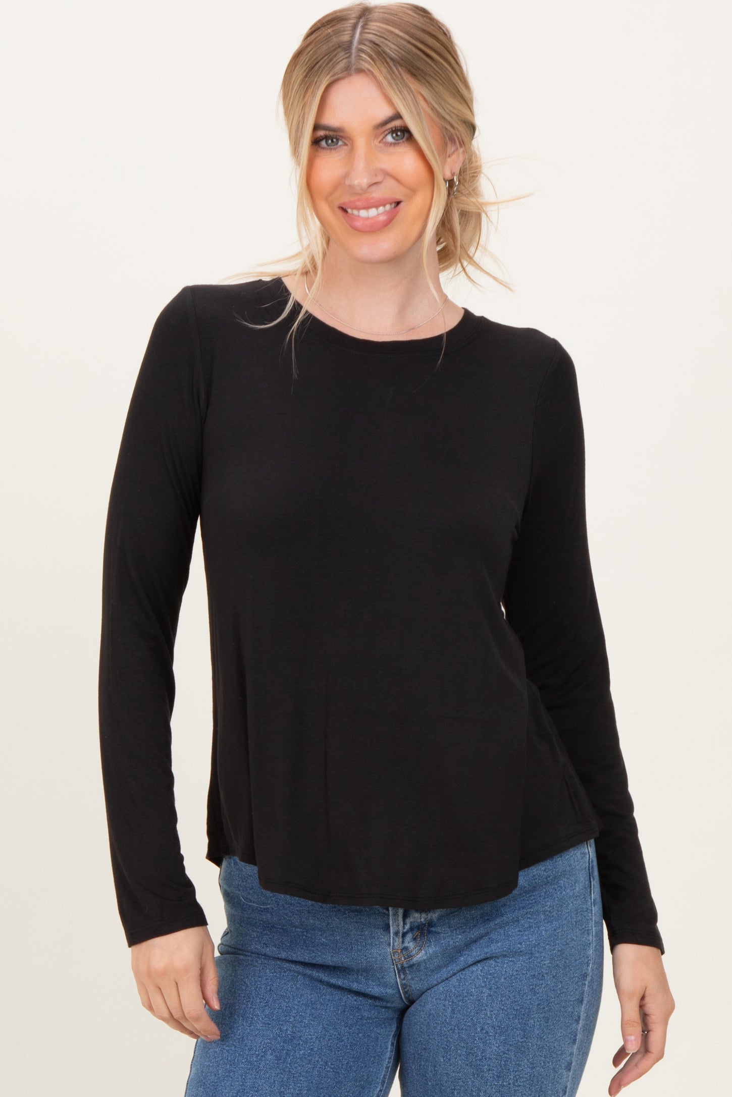 woman wearing a black long sleeve top with a relaxed fit and round neckline paired with blue jeans