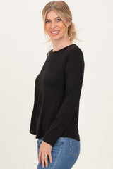 woman wearing a black long sleeve top with a relaxed fit and paired with light blue jeans