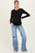 woman wearing a black long sleeve maternity top and distressed light blue maternity jeans, showing her baby bump