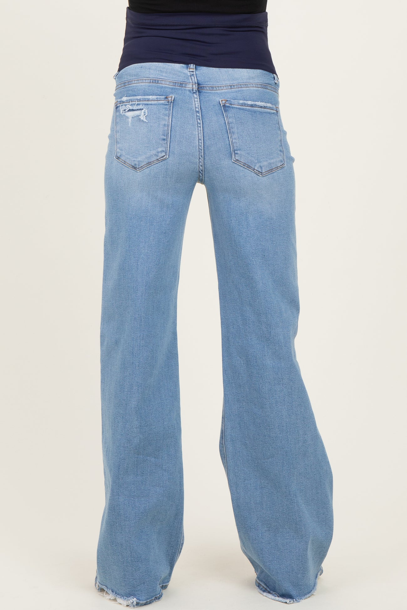 woman wearing a pair of light blue maternity jeans with a relaxed fit and distressed details, viewed from the back