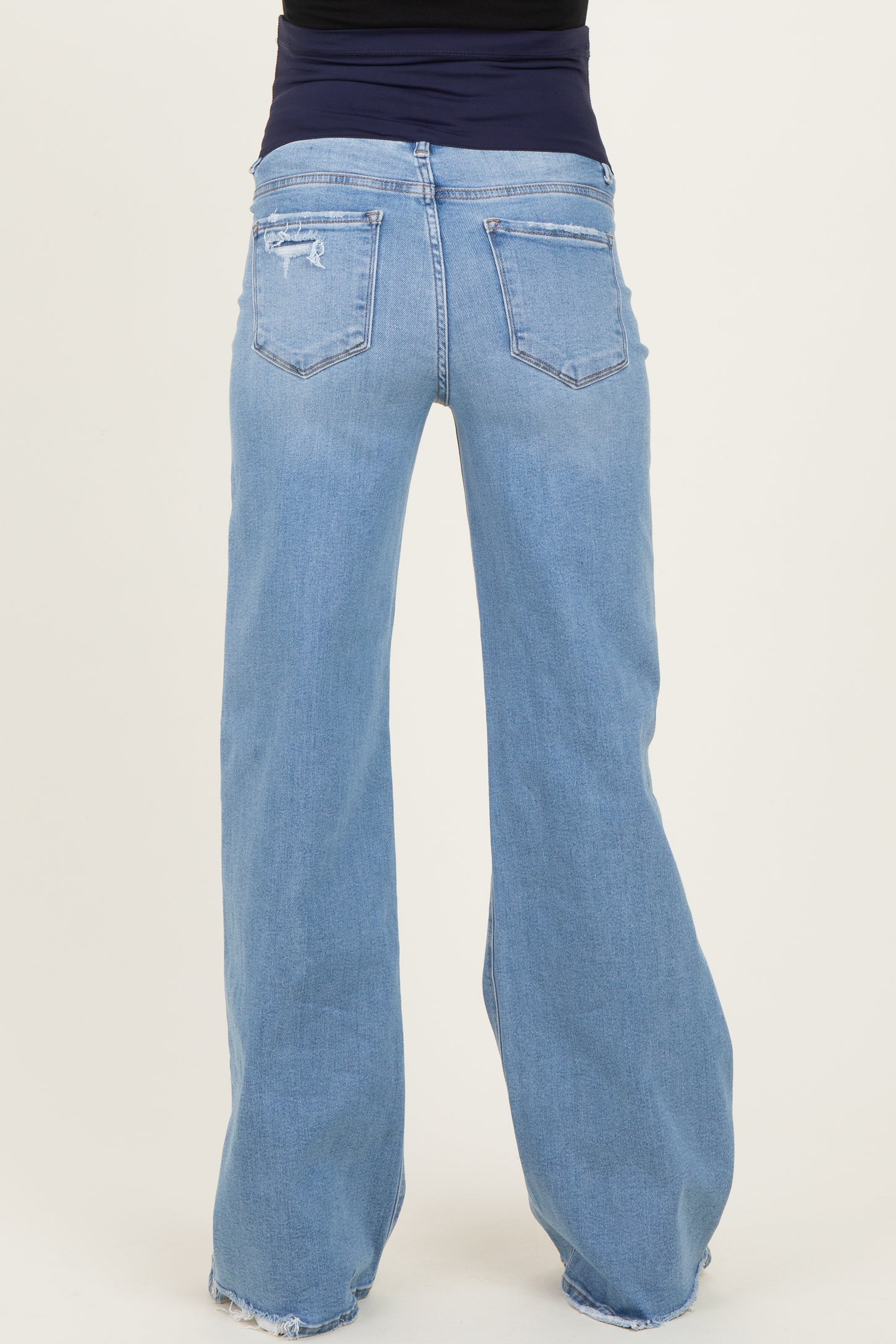 woman wearing a pair of light blue maternity jeans with a relaxed fit and distressed details, viewed from the back