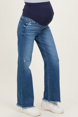 woman wearing dark blue maternity jeans with a belly panel and frayed hem, showing a baby bump