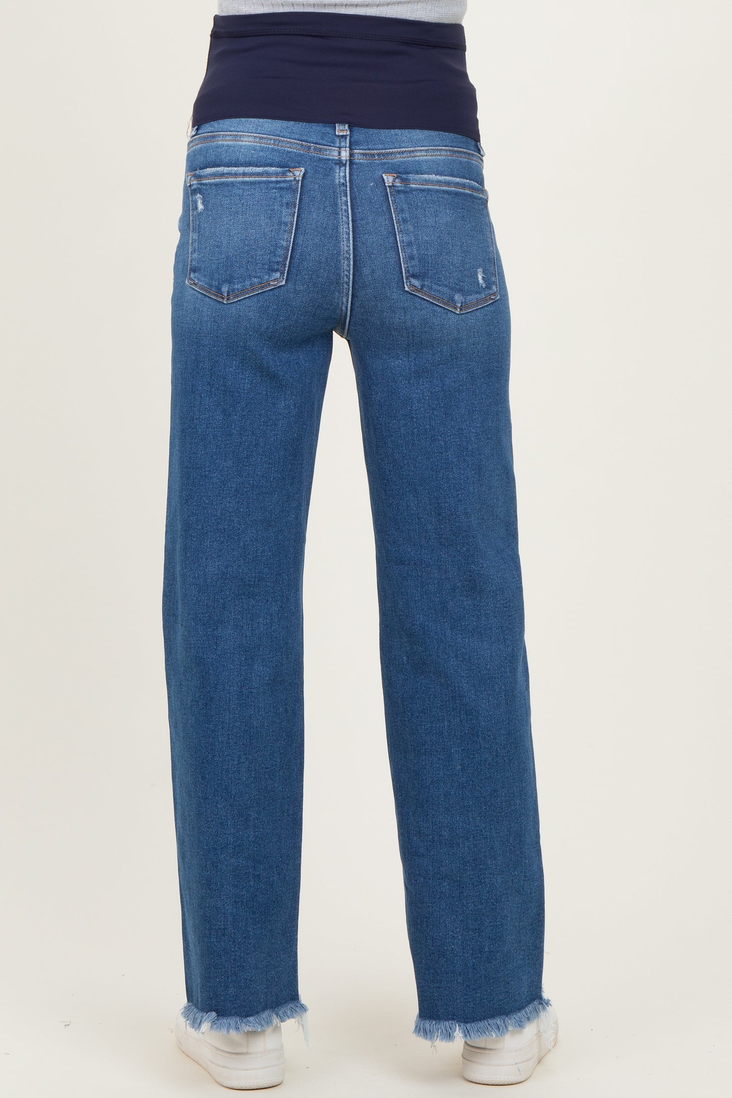 woman wearing blue wide-leg maternity jeans with a stretchable navy waistband and frayed hem at the bottom