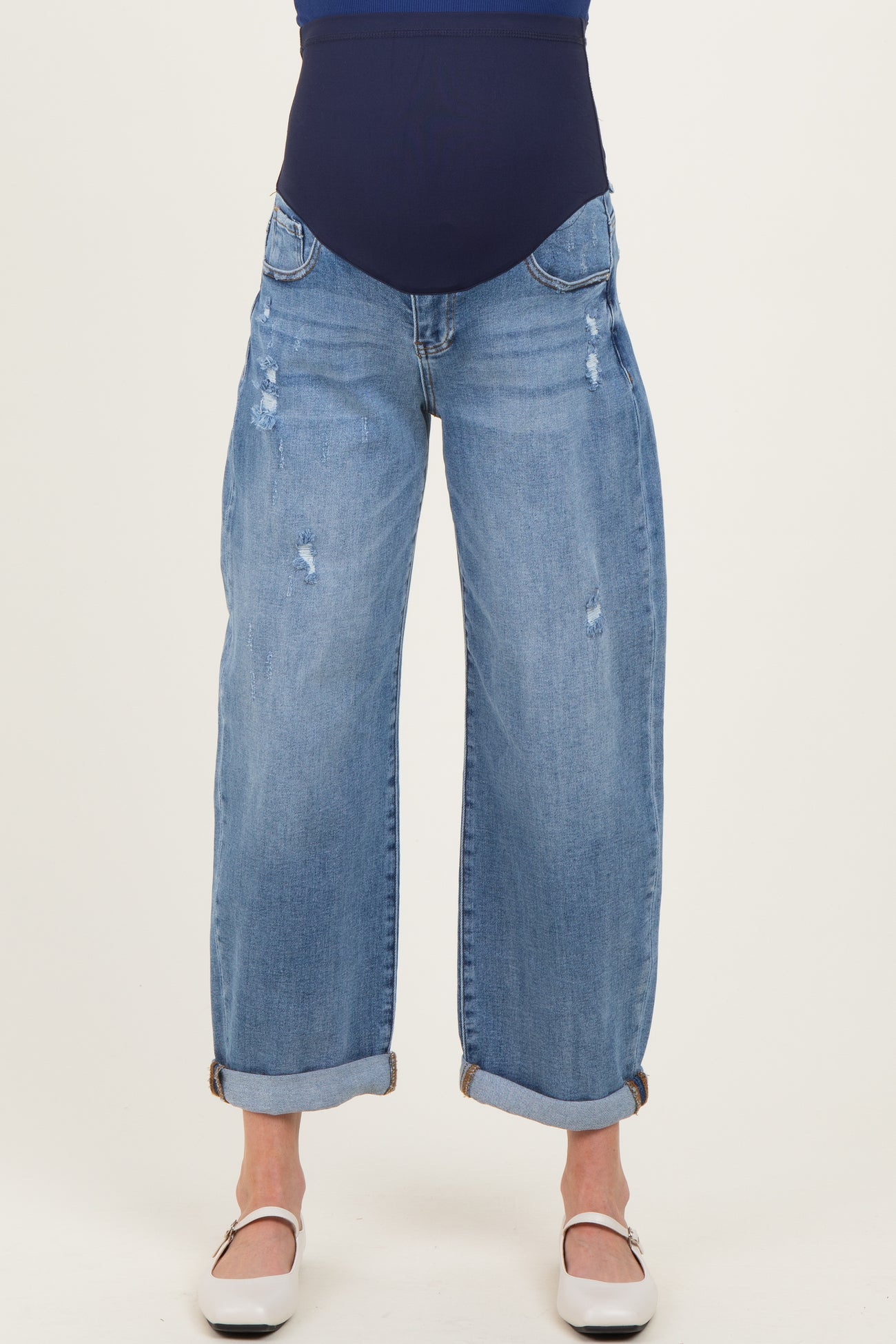 woman wearing a pair of light blue distressed maternity jeans with a wide leg and cuffed hem