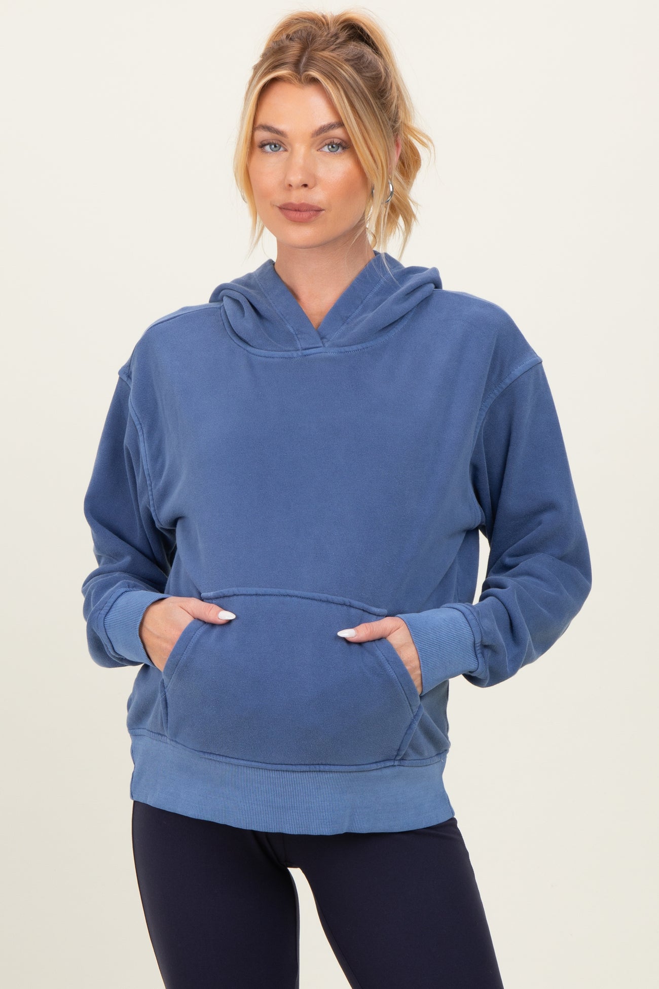 woman wearing a blue maternity hoodie with a front pocket and relaxed fit, showcasing a baby bump