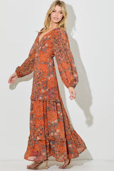 woman wearing a long tiered rust floral maxi dress with puff sleeves and a deep v-neckline