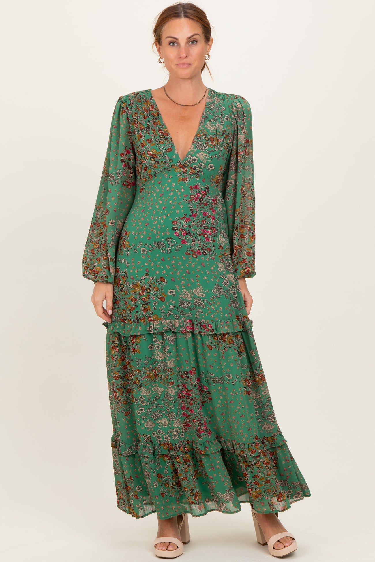 woman wearing a green floral maxi dress with a v-neck and tiered hem
