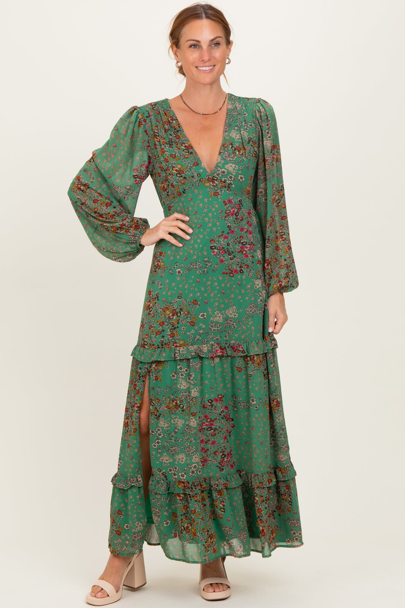 woman wearing a green floral maxi dress with long sleeves, deep v-neck, and tiered ruffles