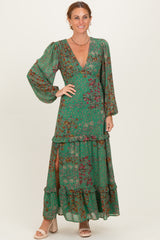 woman wearing a green floral maxi dress with long sleeves, deep v-neck, and tiered ruffles