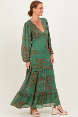 woman wearing a green floral maxi dress with a deep v-neck and long sleeves, styled with chunky heeled sandals