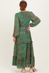 woman wearing a green floral maxi dress with long sleeves and tiered ruffles, showing the back view
