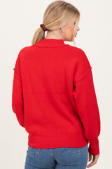 woman wearing a red oversized sweater, shown from the back, paired with blue jeans