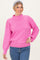 woman wearing a bright pink ribbed sweater with a mock neck and balloon sleeves, paired with blue jeans