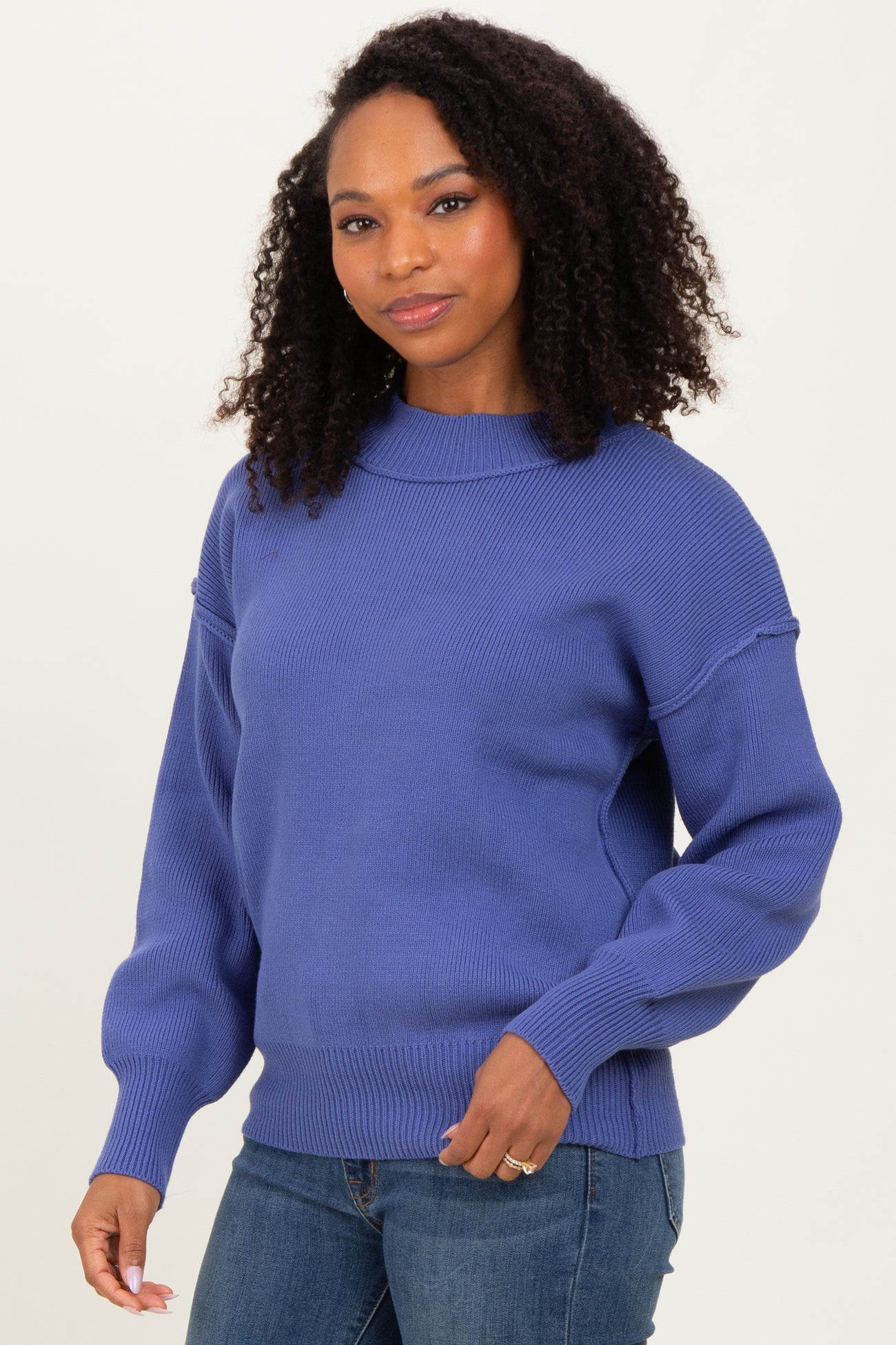 woman wearing a purple oversized sweater with balloon sleeves and a ribbed hem, paired with jeans