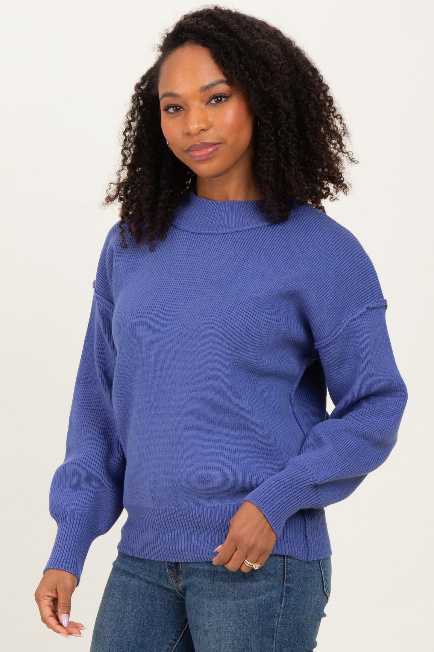 woman wearing a purple oversized sweater with balloon sleeves and a ribbed hem, paired with jeans