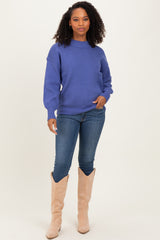 woman wearing a purple oversized sweater with long sleeves and blue skinny jeans, paired with beige knee-high boots