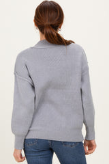 woman wearing a cozy light gray loose-fit sweater with a ribbed texture, seen from the back