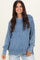 woman wearing a blue ribbed oversized sweater with a high neckline and side slits