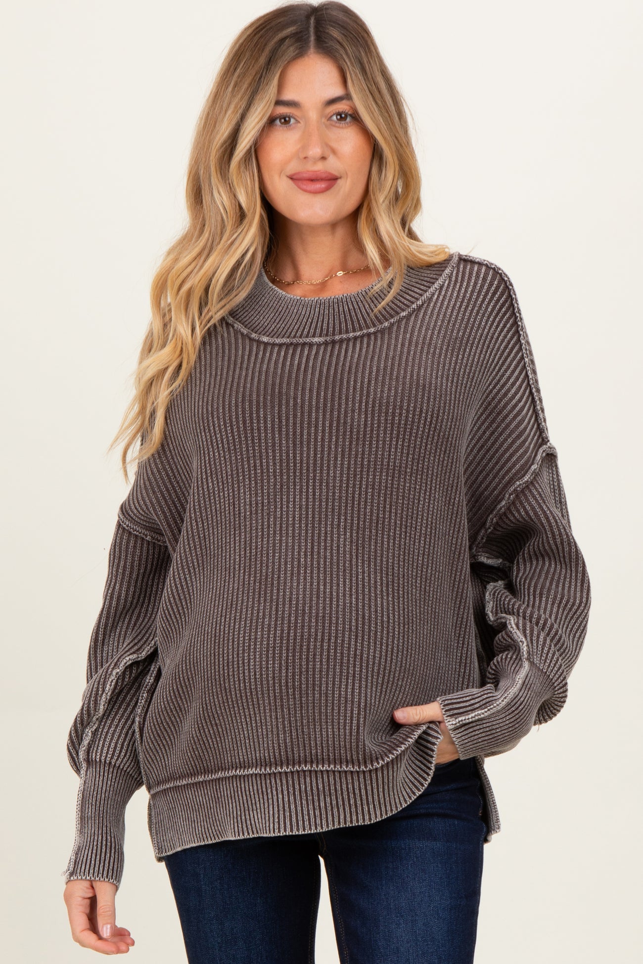 woman wearing a gray ribbed maternity sweater with a relaxed fit and long sleeves, holding her baby bump