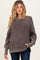 woman wearing a gray ribbed maternity sweater with a relaxed fit and long sleeves, holding her baby bump
