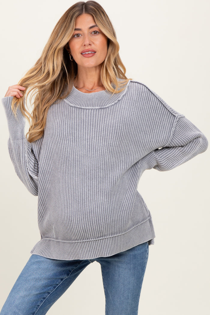 woman wearing a gray ribbed maternity sweater with a loose fit and visible baby bump, paired with blue jeans