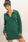 woman wearing a green sweater dress with a collar and long sleeves, posing with one hand on her hip