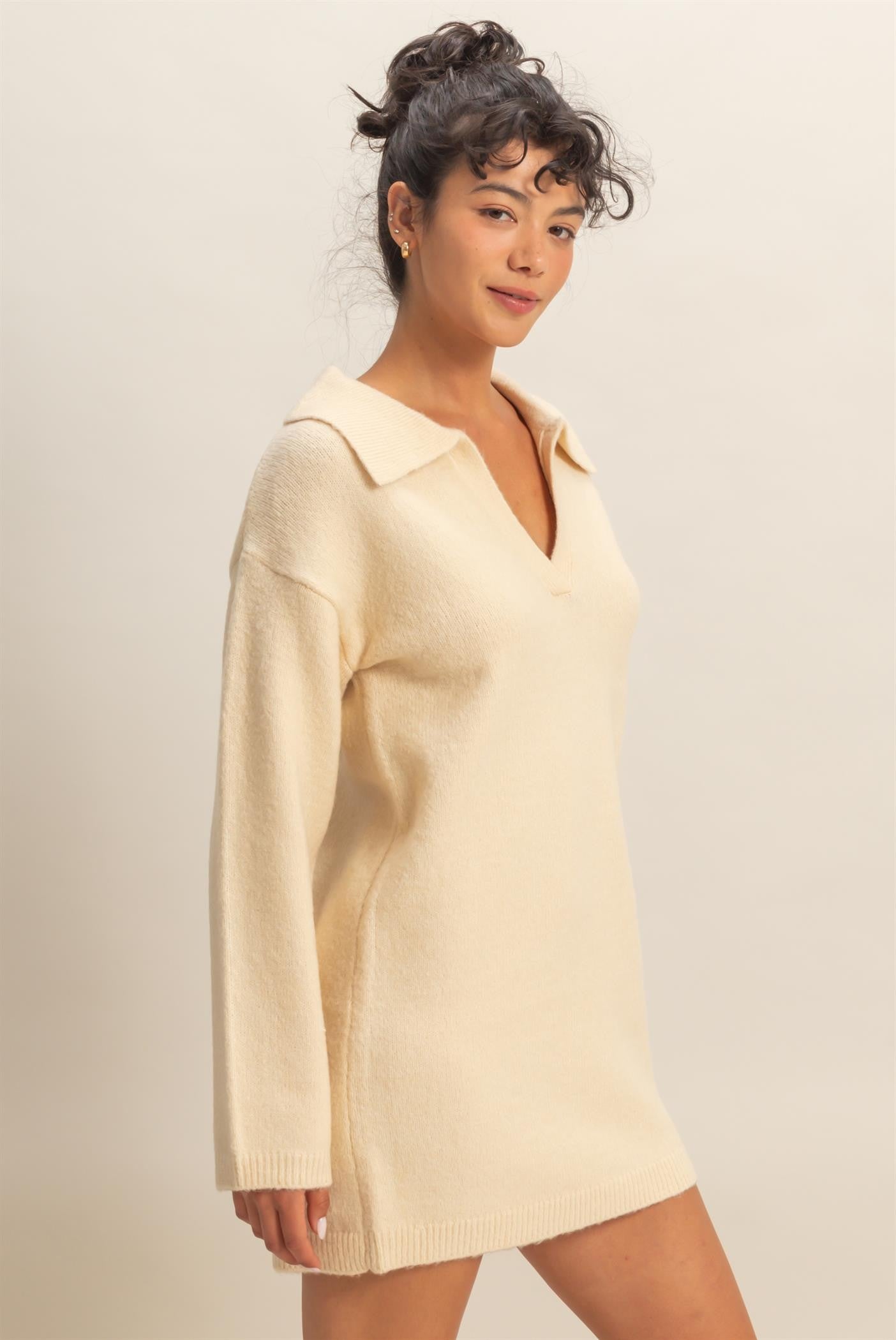 woman wearing a cream oversized sweater dress with a v-neck and collared neckline
