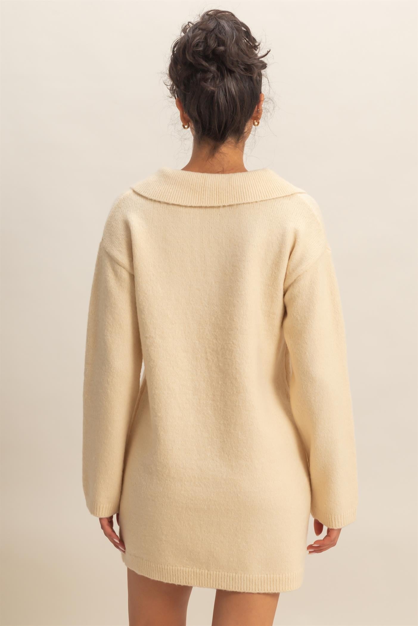 woman wearing a cozy cream-colored oversized sweater dress with a wide collar and long sleeves