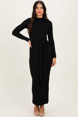 woman wearing a black ribbed knit maxi dress with long sleeves and a tie belt at the waist