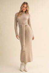 woman wearing a beige ribbed knit long sleeve maxi dress with a tied waist detail and white ankle boots
