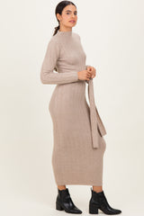 woman wearing a beige ribbed long sleeve midi dress with a waist tie and black ankle boots