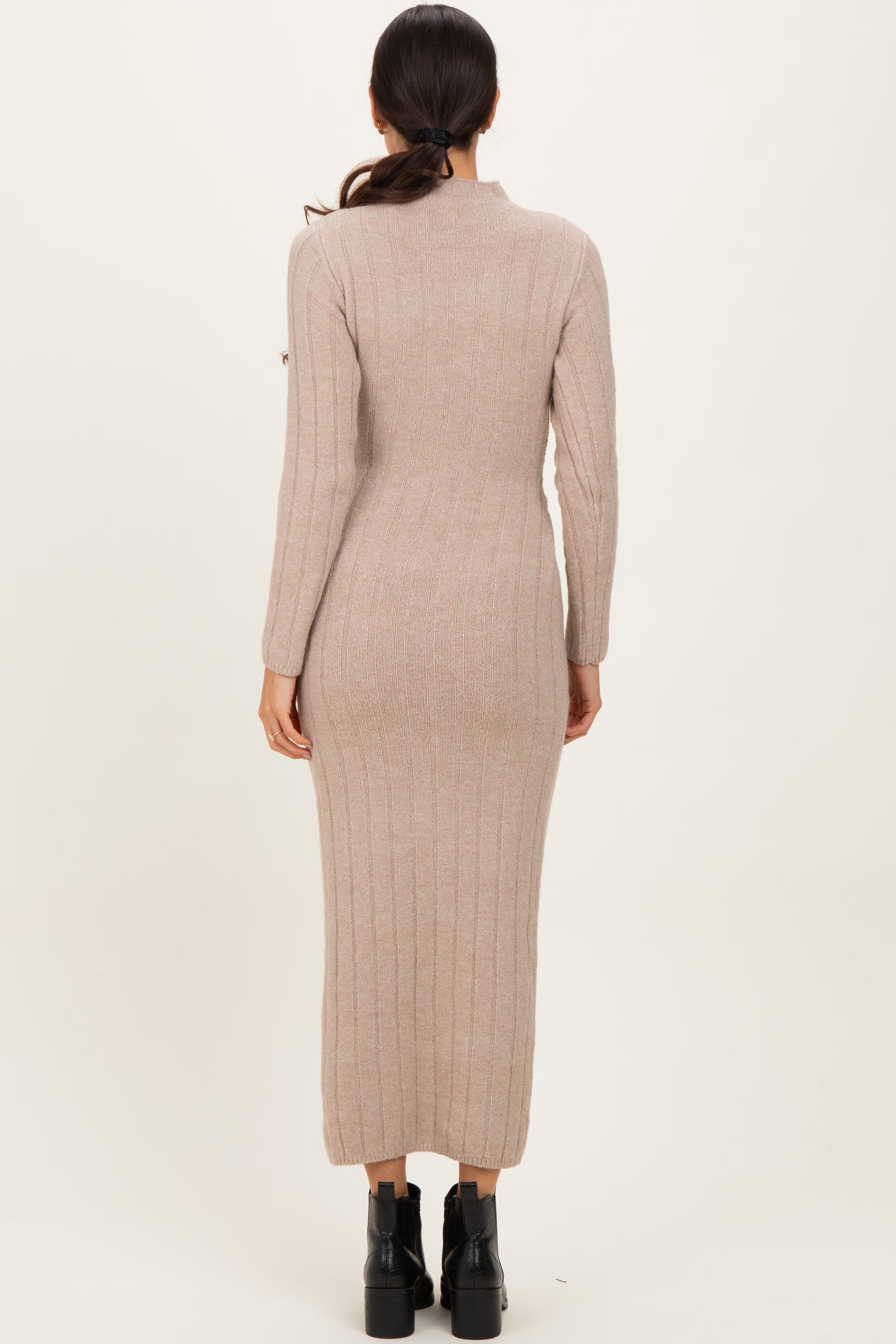 woman wearing a long beige ribbed knit dress with long sleeves and a fitted silhouette from the back