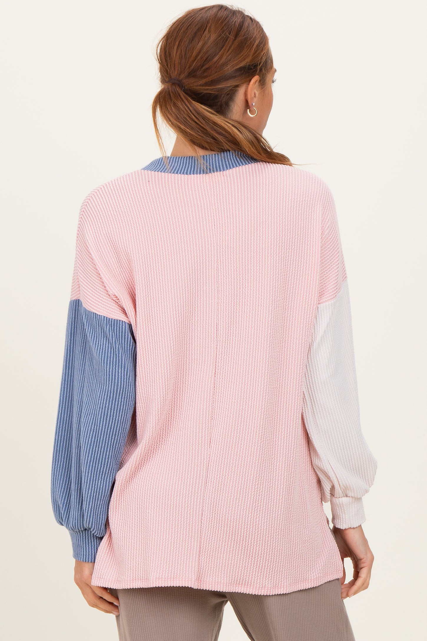 woman wearing a color-block long sleeve top in pink, blue, and white with a loose fit and ribbed texture from the back