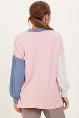 woman wearing a color-block long sleeve top in pink, blue, and white with a loose fit and ribbed texture from the back