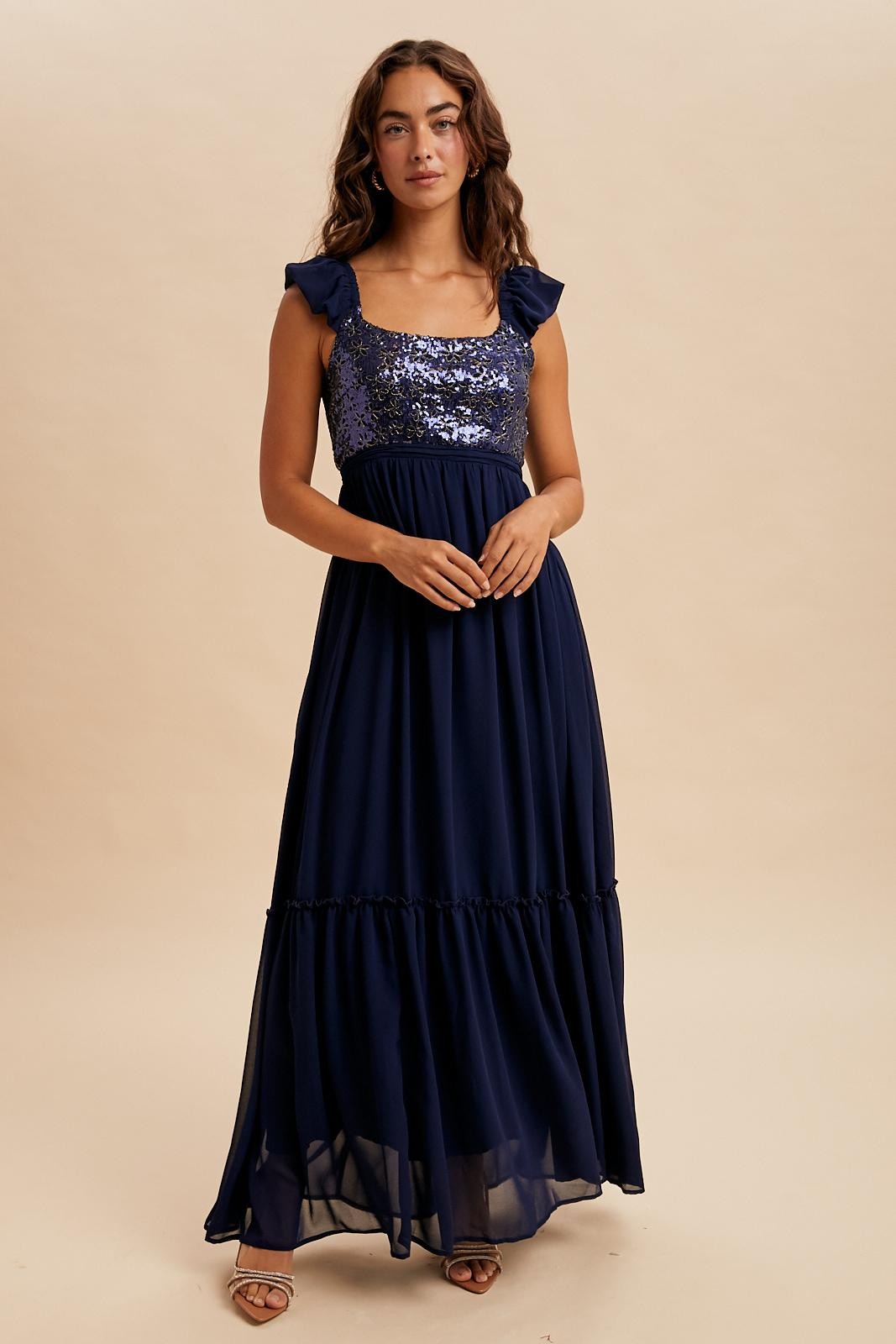 woman wearing a navy blue maxi dress with sequin details and ruffled straps
