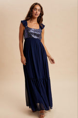 woman wearing a navy blue maxi dress with sequined bodice and ruffled sleeves