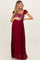 woman wearing a burgundy maternity maxi dress with a sequin bodice and ruffled sleeves, holding her baby bump