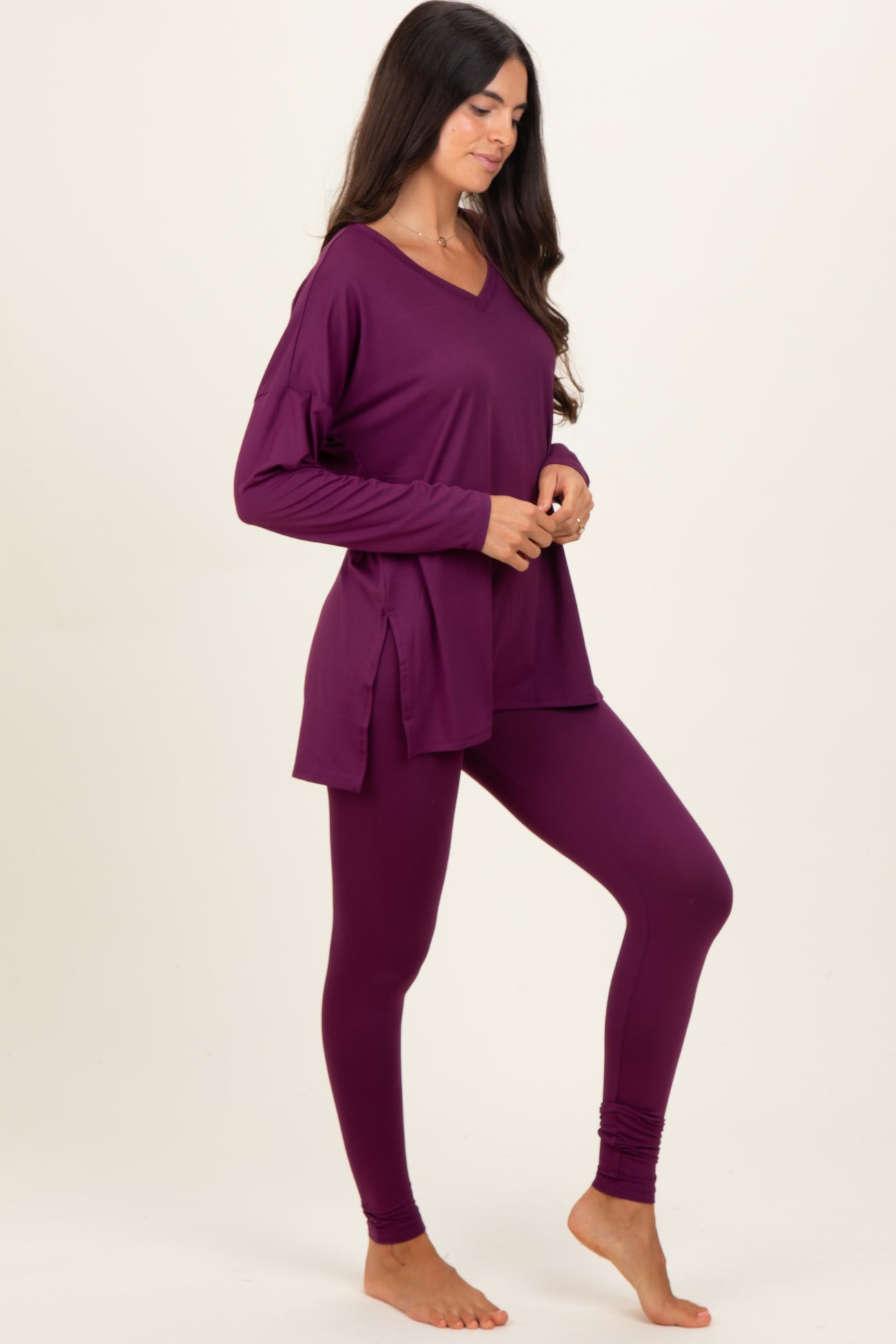 woman wearing a purple long sleeve top with side slits and matching purple leggings