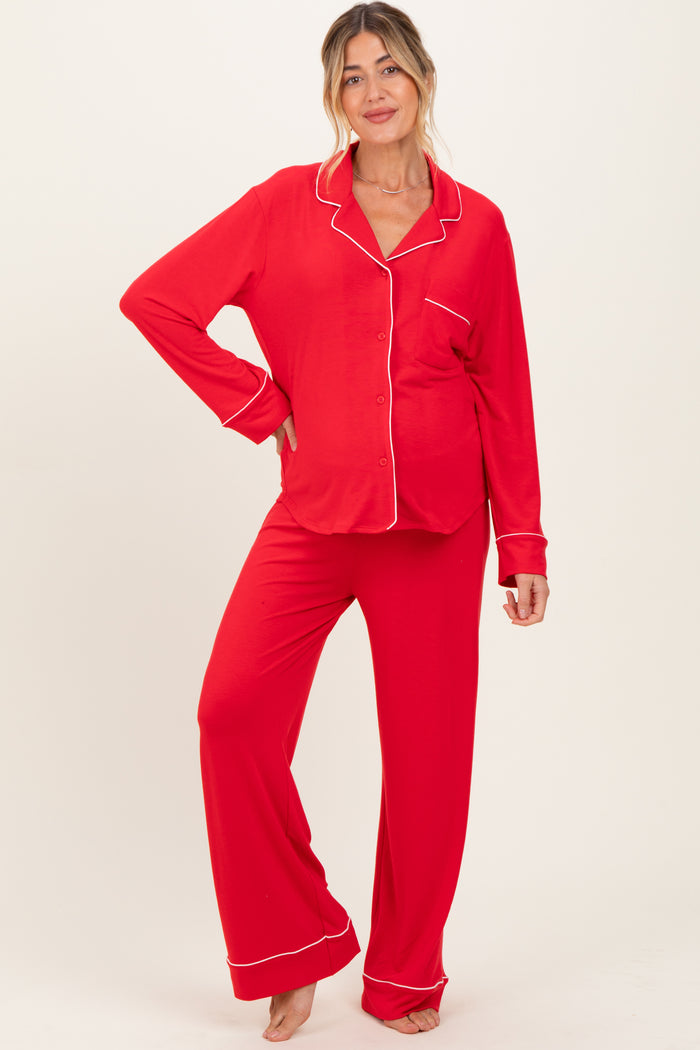 woman wearing a red maternity pajama set with white piping and a visible baby bump