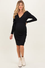woman wearing a black ribbed maternity dress with a wrap style and long sleeves, showing her baby bump